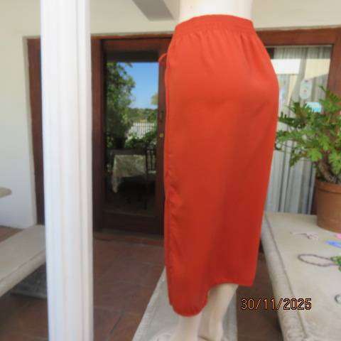 Burnt orange ankle length polyester skirt with front button decoration. Elastic waistband. Size 40