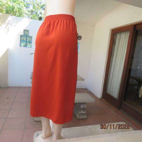 Burnt orange ankle length polyester skirt with front button decoration. Elastic waistband. Size 40