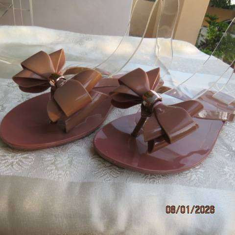 Pair of brownish pink flat sandals in bendable plastic with pretty bow. Size 8