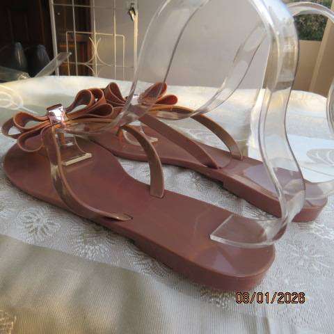 Pair of brownish pink flat sandals in bendable plastic with pretty bow. Size 8