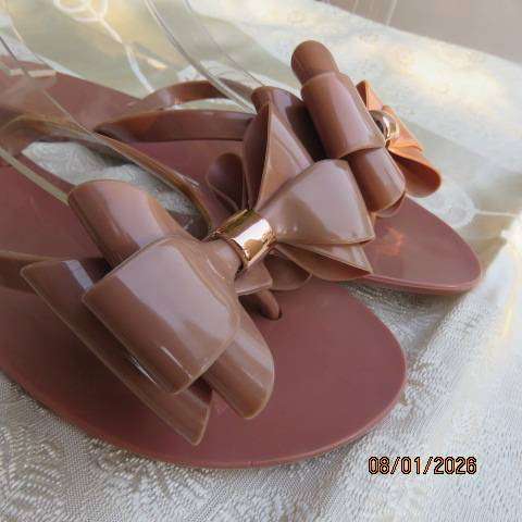 Pair of brownish pink flat sandals in bendable plastic with pretty bow. Size 8