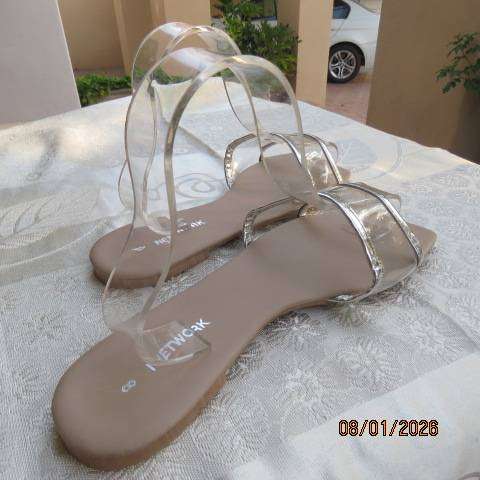 Pair of flip flop sandals with clear band with silver over foot. Never worn. Size 8