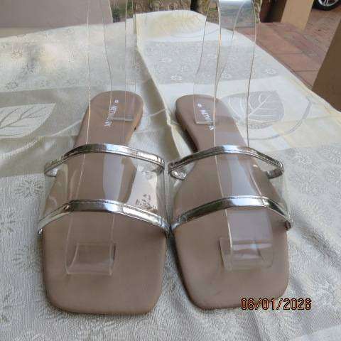 Pair of flip flop sandals with clear band with silver over foot. Never worn. Size 8