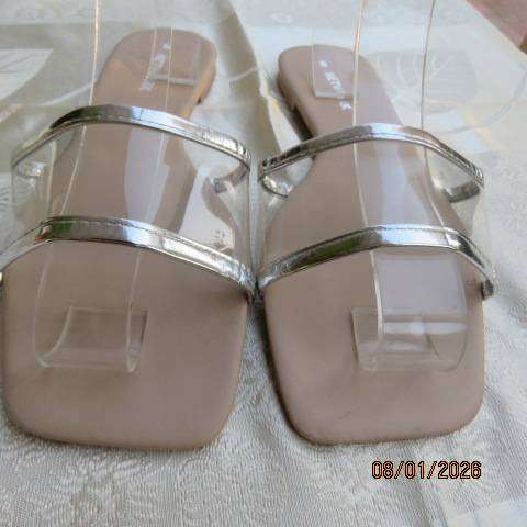 Pair of flip flop sandals with clear band with silver over foot. Never worn. Size 8