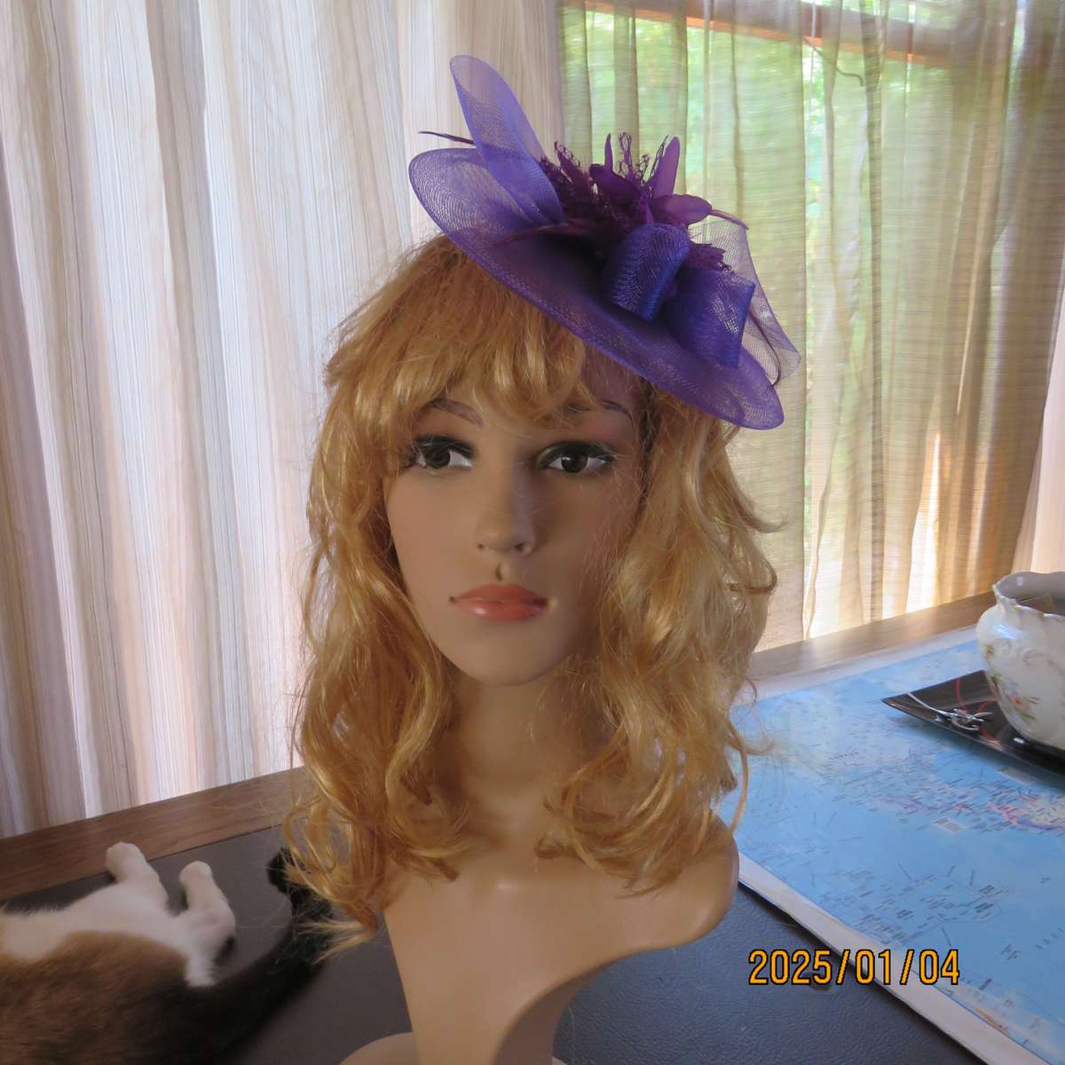 Dainty purple fascinator hat for special occasion. In mesh with bow-flower and feathers. Alice band