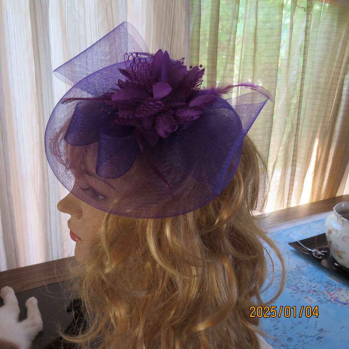 Dainty purple fascinator hat for special occasion. In mesh with bow-flower and feathers. Alice band