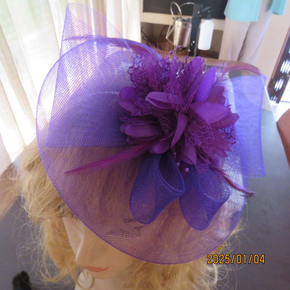 Dainty purple fascinator hat for special occasion. In mesh with bow-flower and feathers. Alice band