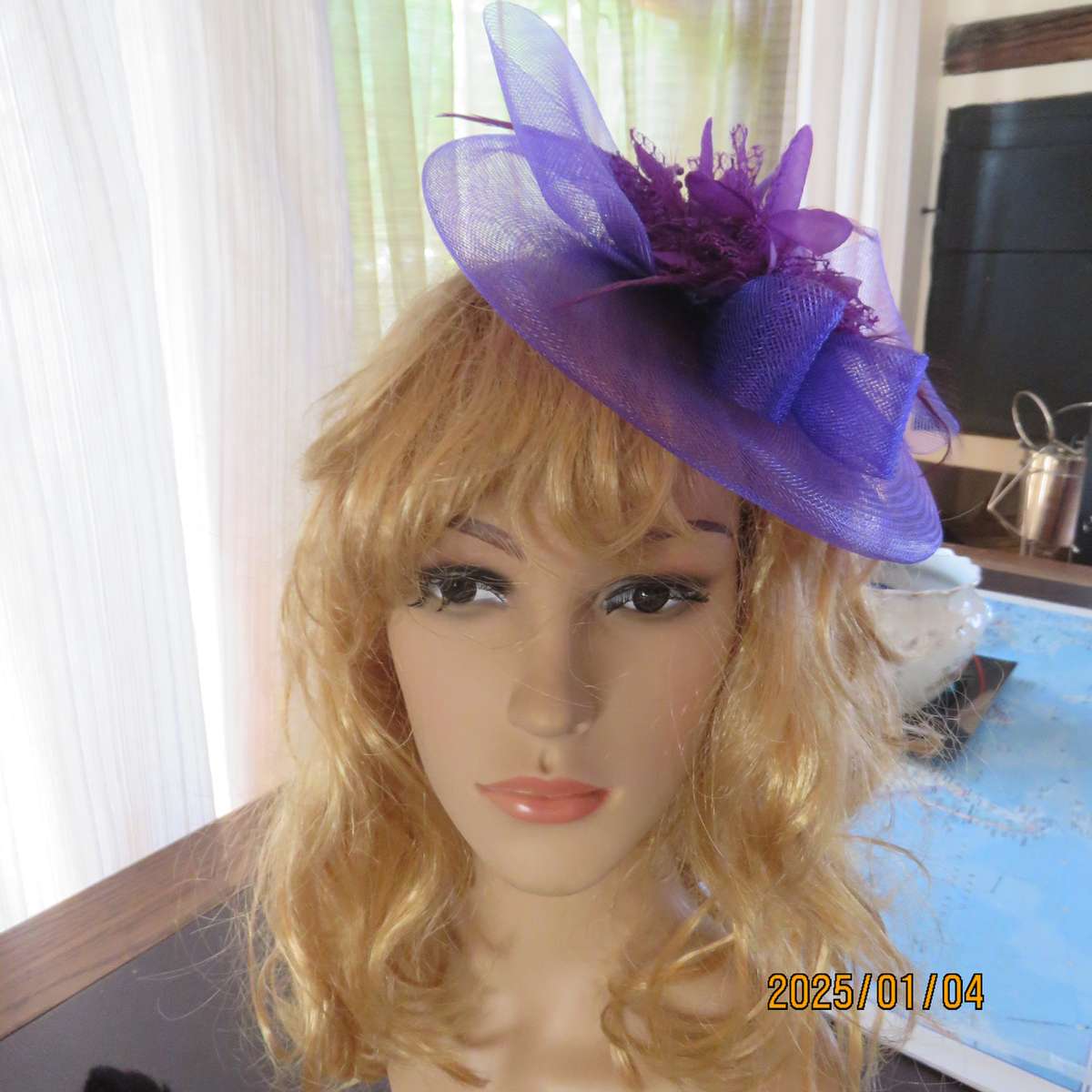 Dainty purple fascinator hat for special occasion. In mesh with bow-flower and feathers. Alice band