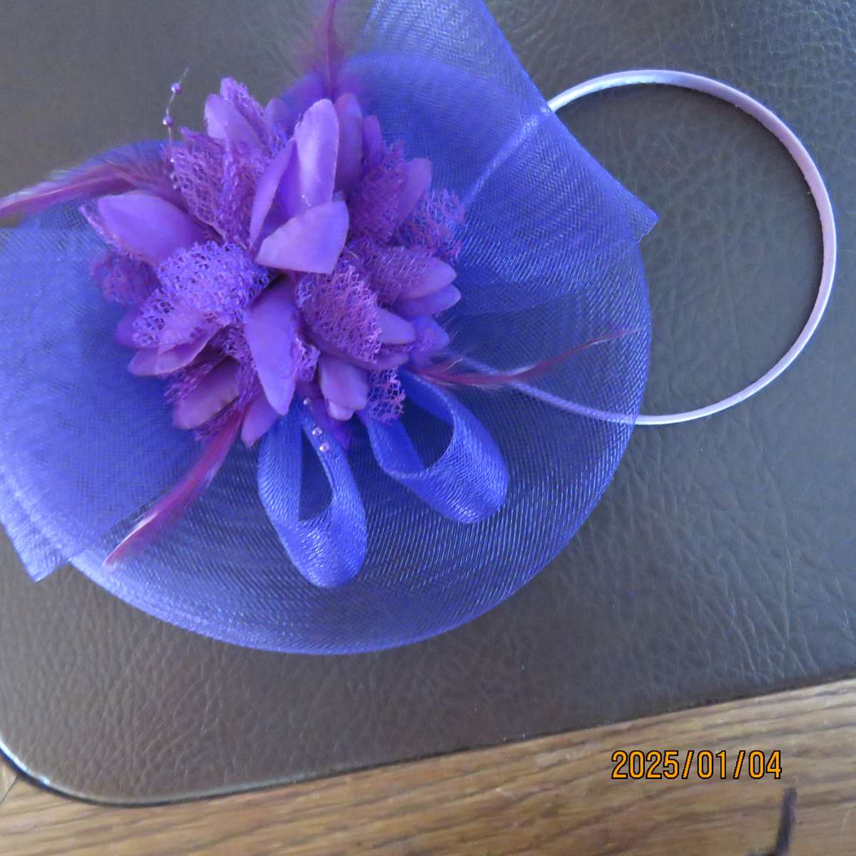 Dainty purple fascinator hat for special occasion. In mesh with bow-flower and feathers. Alice band