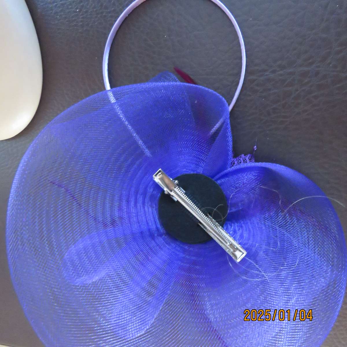 Dainty purple fascinator hat for special occasion. In mesh with bow-flower and feathers. Alice band