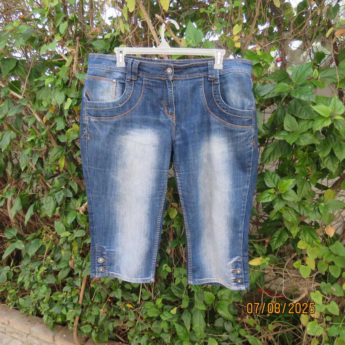 Blue denim tapered leg cropped pants size 44. Two button hem opening.