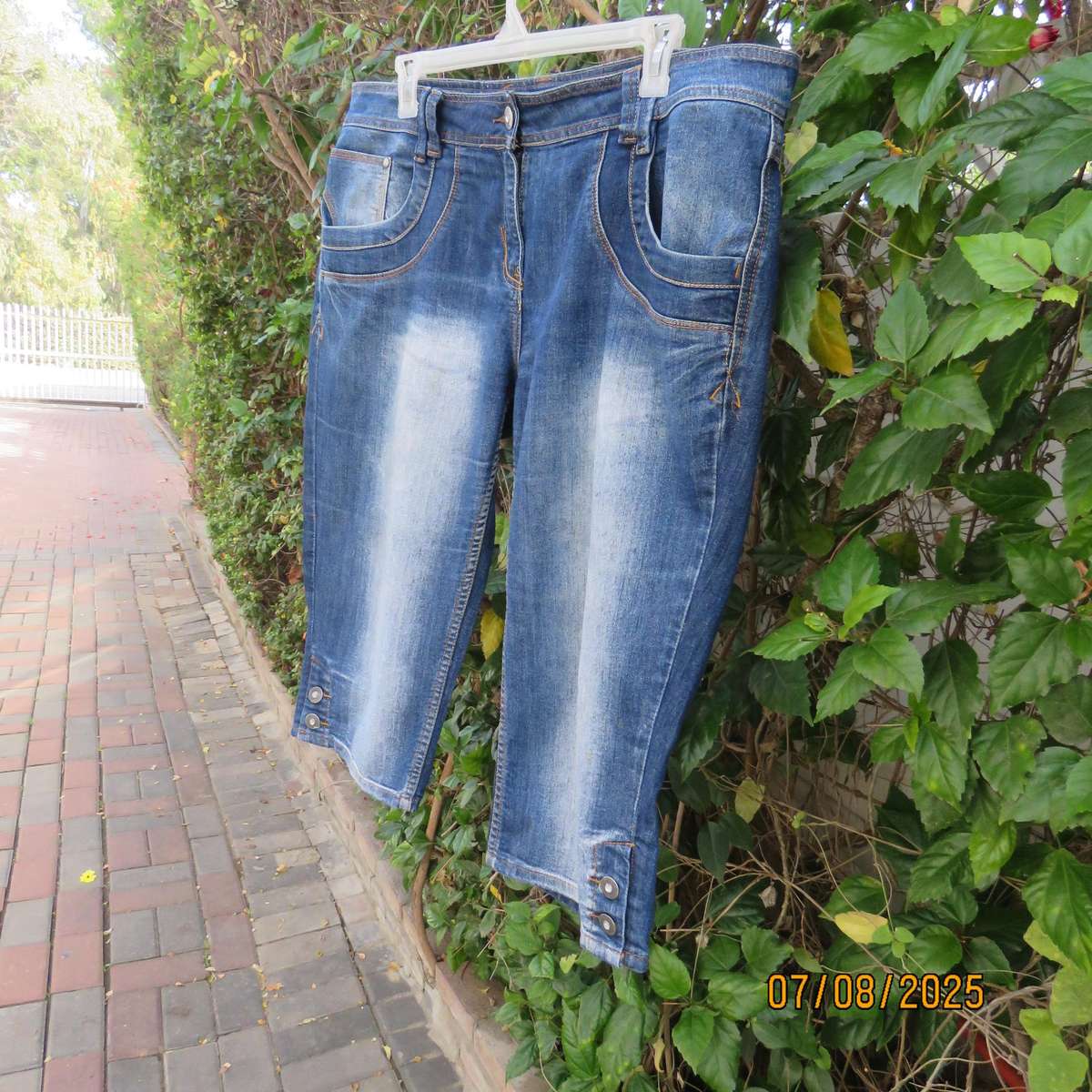 Blue denim tapered leg cropped pants size 44. Two button hem opening.