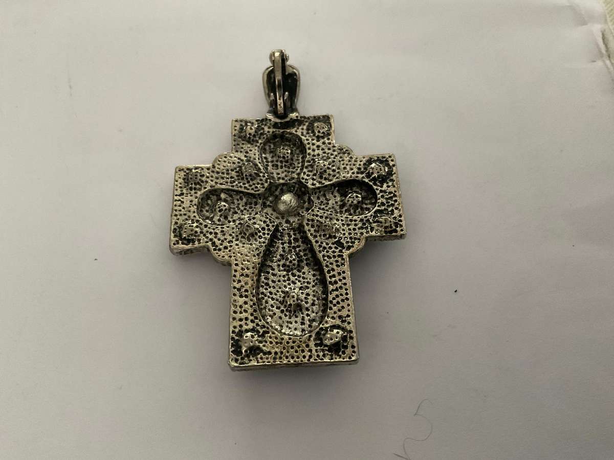 A silver metal cross with white rhinestones