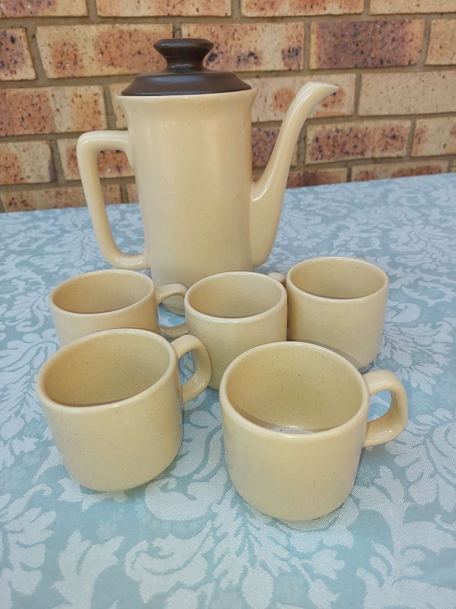 A BEIGE DESERT STONEWARE  COFFEE SET OF FIVE CUPS AND A JUG  SOLD AS IS
