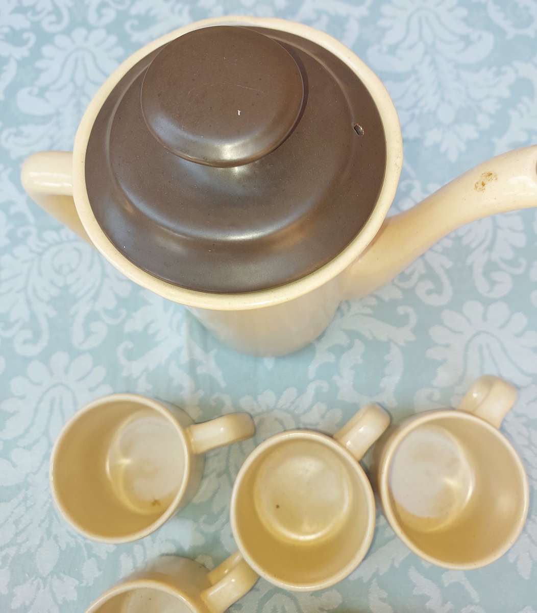 A BEIGE DESERT STONEWARE  COFFEE SET OF FIVE CUPS AND A JUG  SOLD AS IS