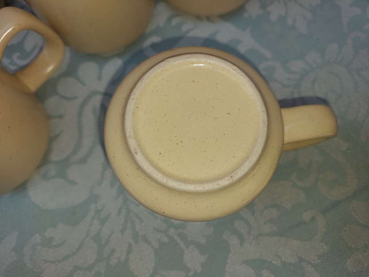 A BEIGE DESERT STONEWARE  COFFEE SET OF FIVE CUPS AND A JUG  SOLD AS IS