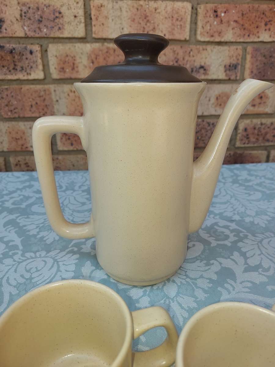 A BEIGE DESERT STONEWARE  COFFEE SET OF FIVE CUPS AND A JUG  SOLD AS IS