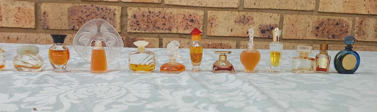 A COLLECTION OF MINITURE LALIQUE PERFUME BOTTLES AND SOME HAVE PERFUMES IN IT SOLD AS IS