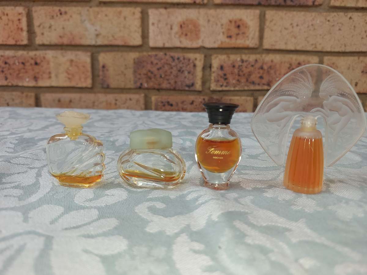 A COLLECTION OF MINITURE LALIQUE PERFUME BOTTLES AND SOME HAVE PERFUMES IN IT SOLD AS IS