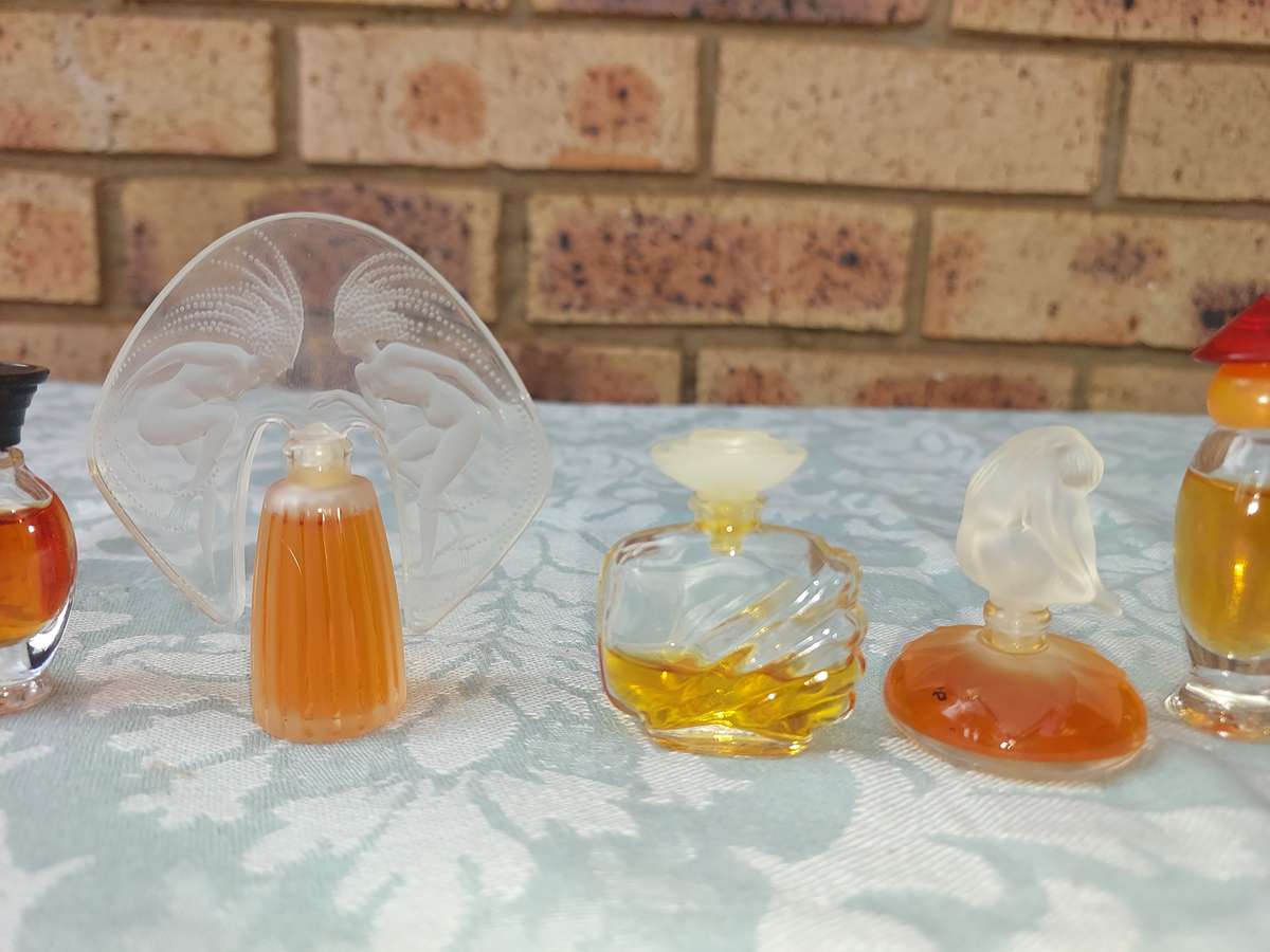 A COLLECTION OF MINITURE LALIQUE PERFUME BOTTLES AND SOME HAVE PERFUMES IN IT SOLD AS IS
