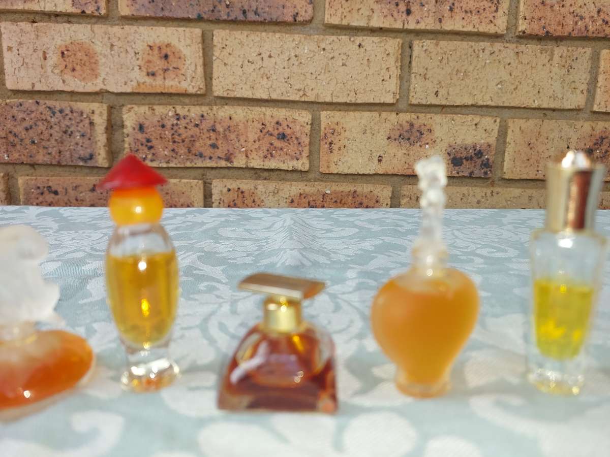 A COLLECTION OF MINITURE LALIQUE PERFUME BOTTLES AND SOME HAVE PERFUMES IN IT SOLD AS IS