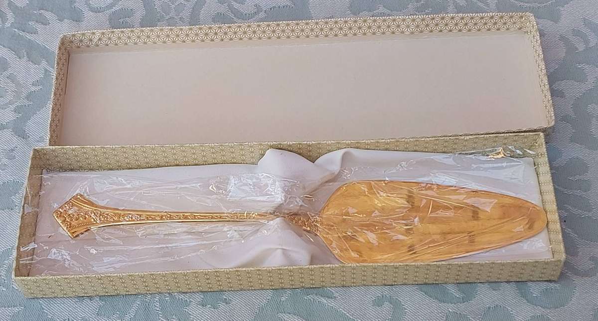 AN EETRITE 24 CARAT GOLD PLATED FLEUR CAKE CUTTER SOLD AS IS