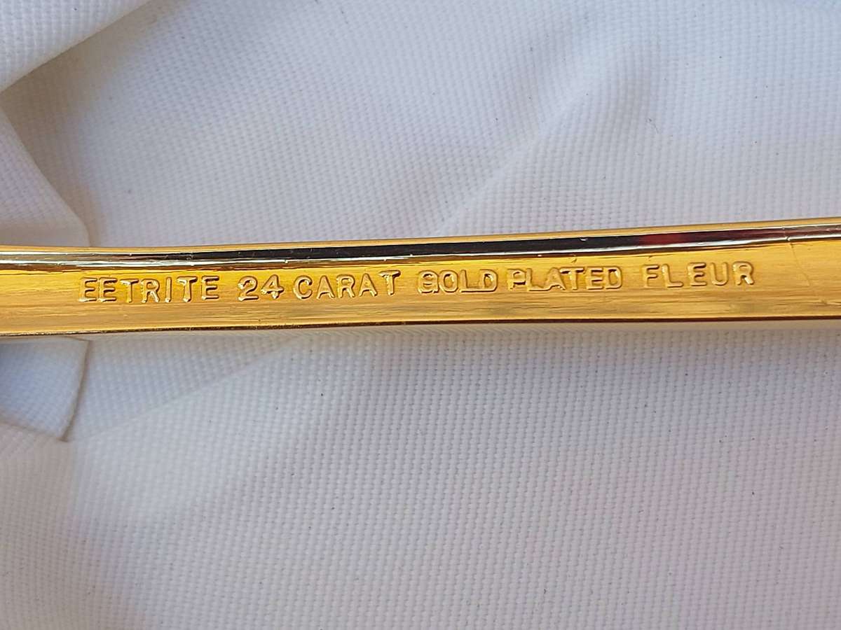 AN EETRITE 24 CARAT GOLD PLATED FLEUR CAKE CUTTER SOLD AS IS