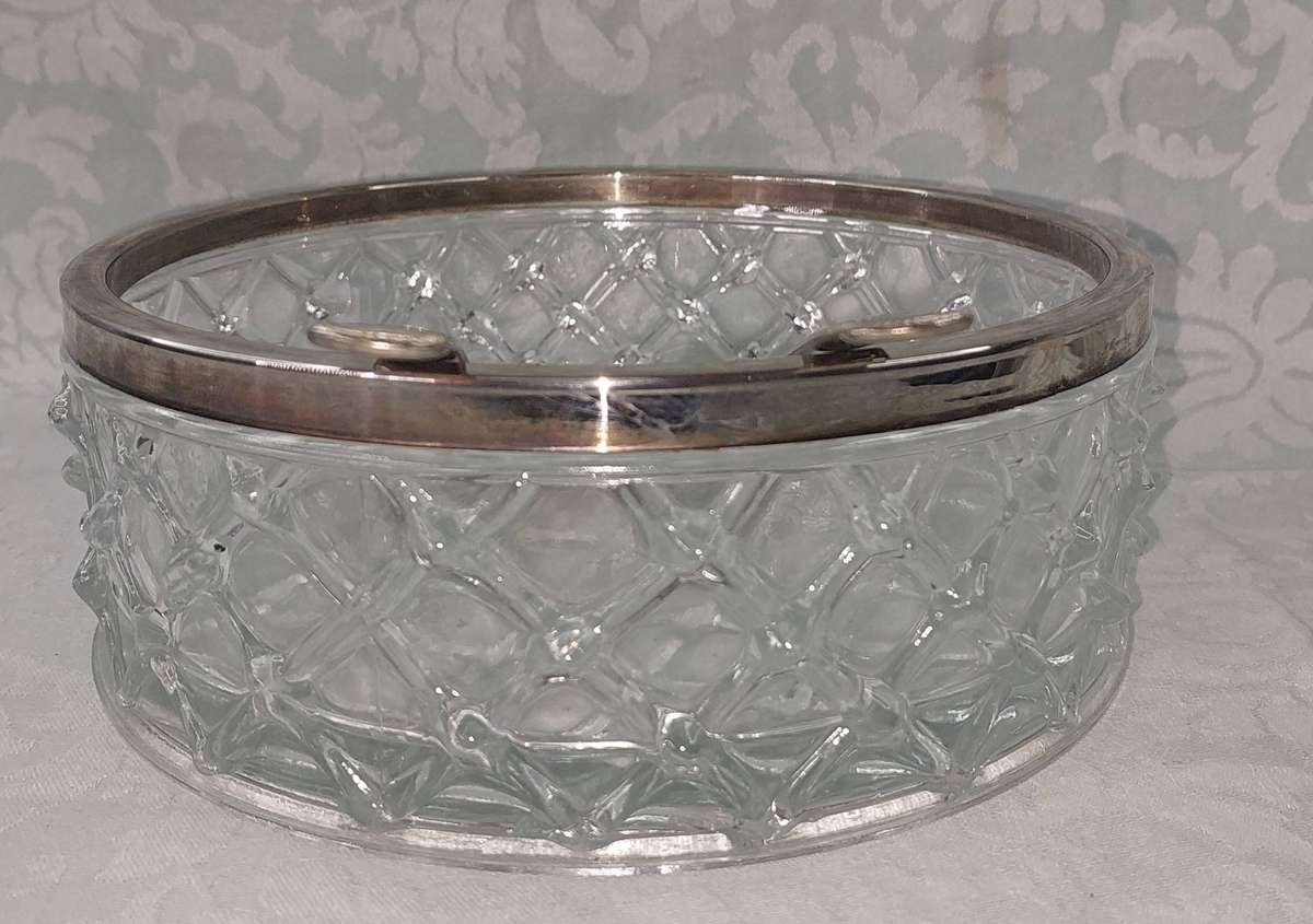 A vintage glass bowl with a diamond pattern and a metallic rim with silver-plated salad tongs