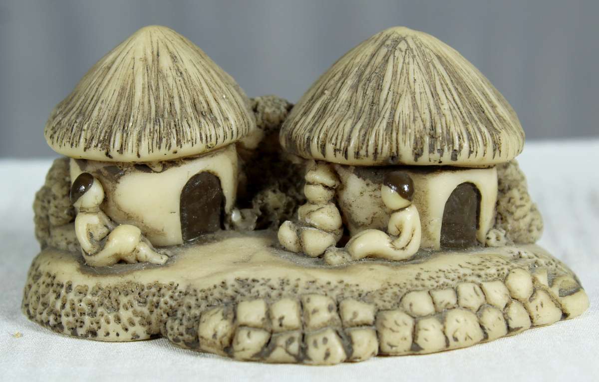 Miniature African huts with people sitting in front