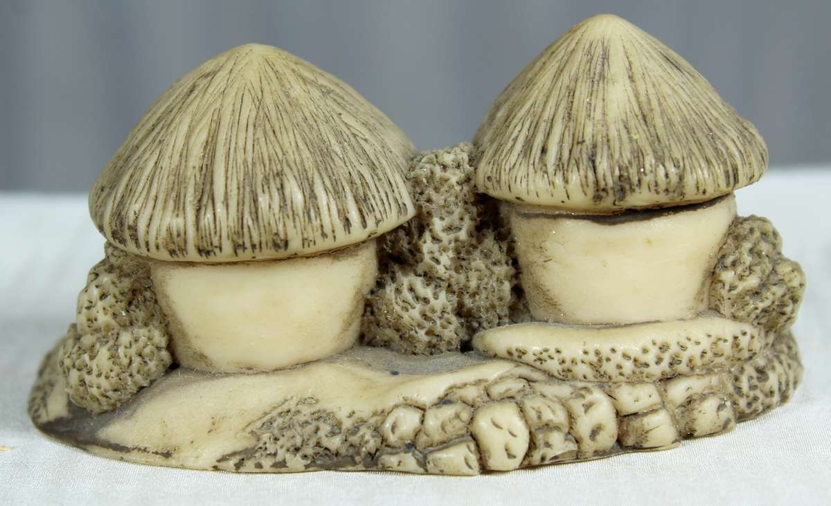 Miniature African huts with people sitting in front