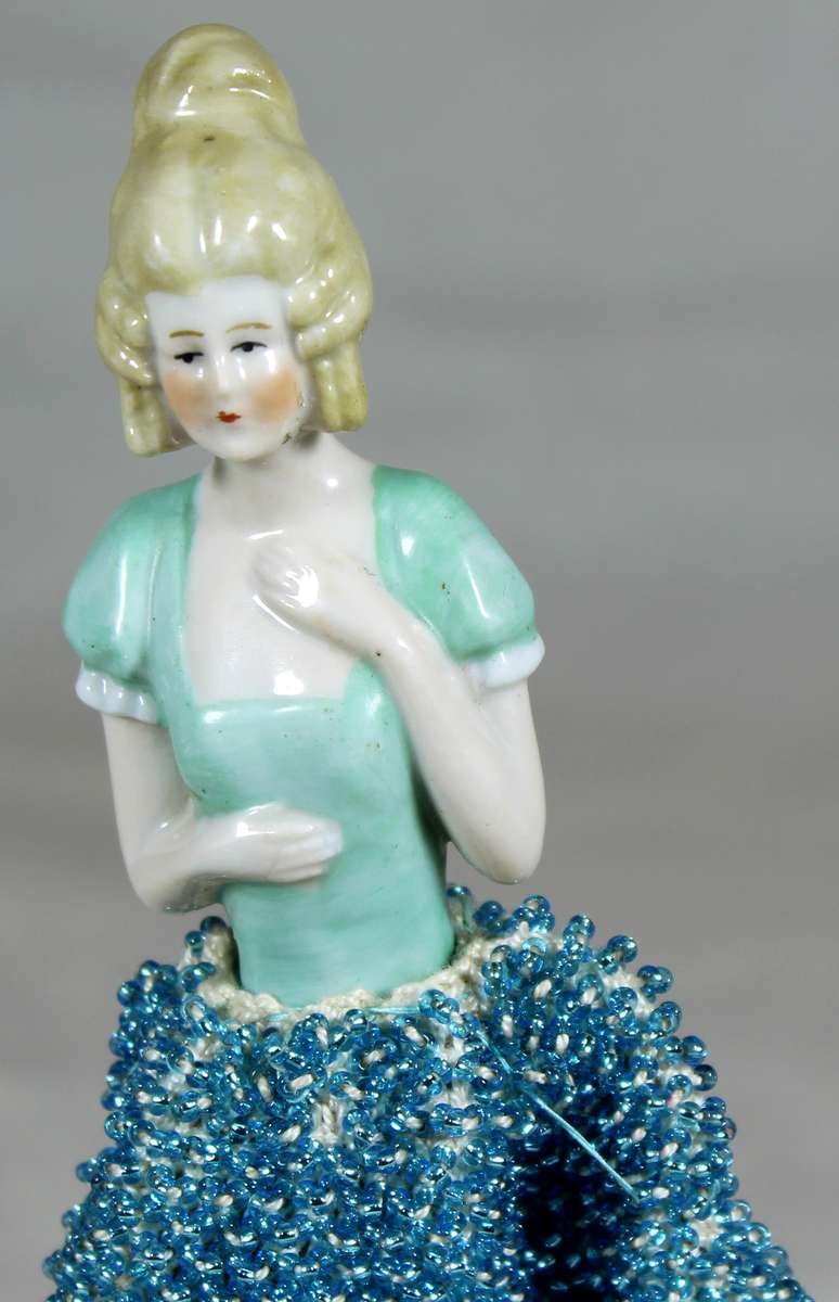 Half doll with beaded sea blue dress on stand