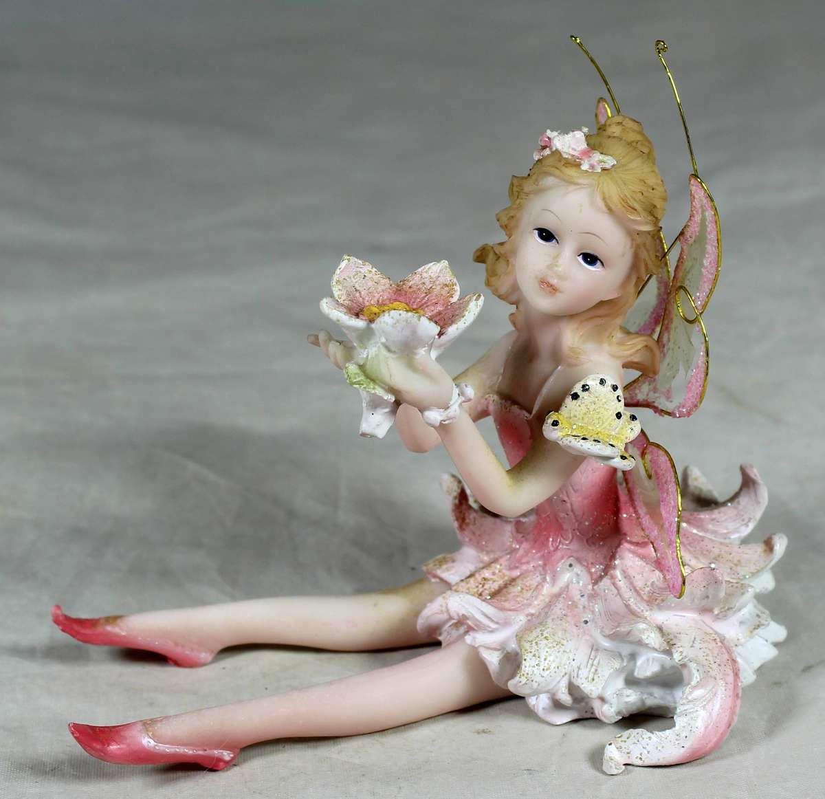 Seated ballerina in pink, holding a large flower