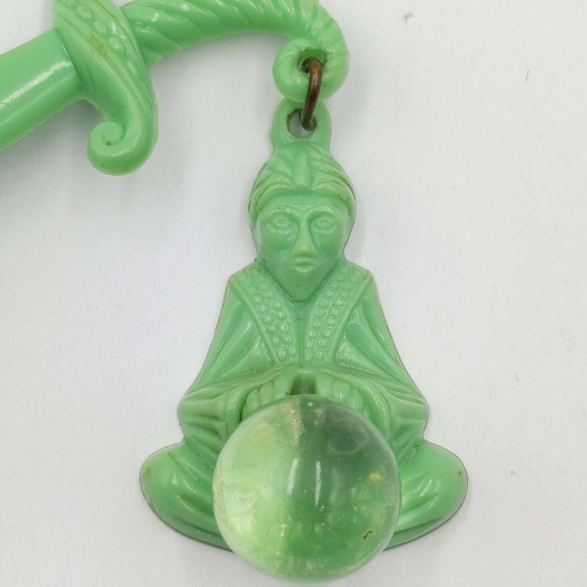 Green lucite brooch with sword and monk with crystal ball