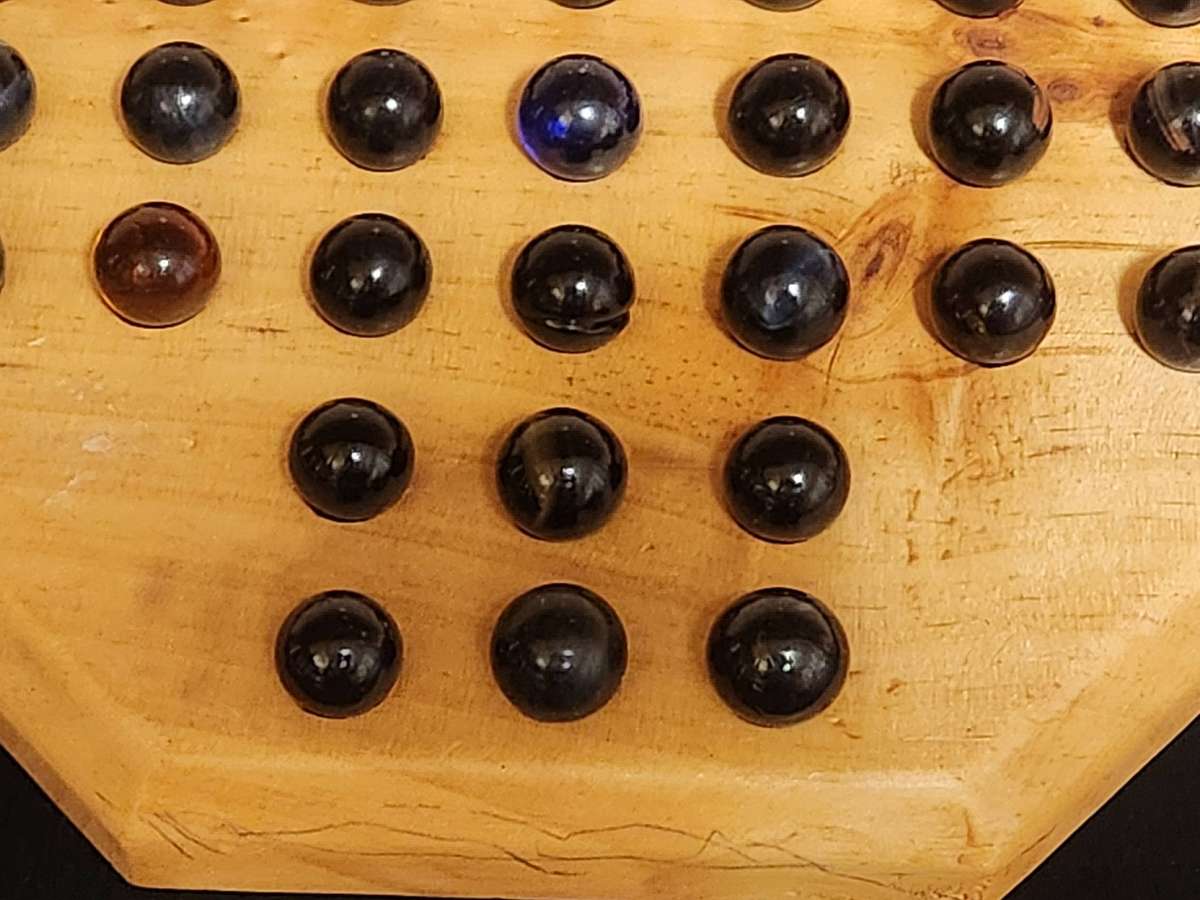 MARBLE SOLITAIRE GAME ON A WOODEN BOARD