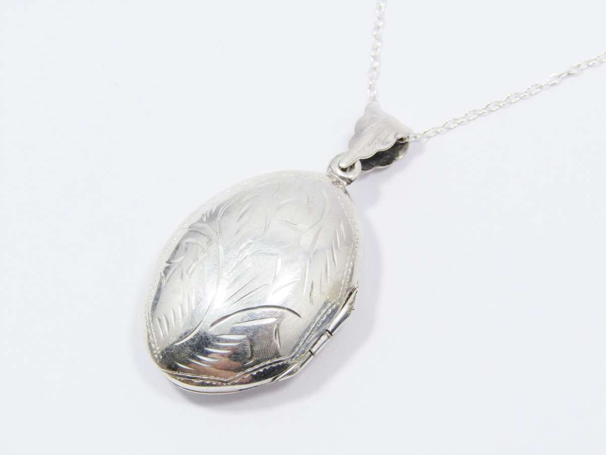 A Lovely Medium Size Oval Engraved Locket On Chain in Sterling Silver.
