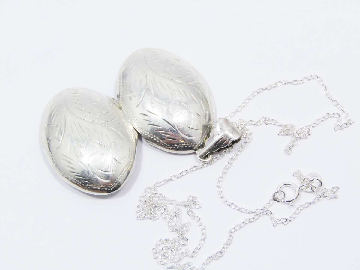 A Lovely Medium Size Oval Engraved Locket On Chain in Sterling Silver.