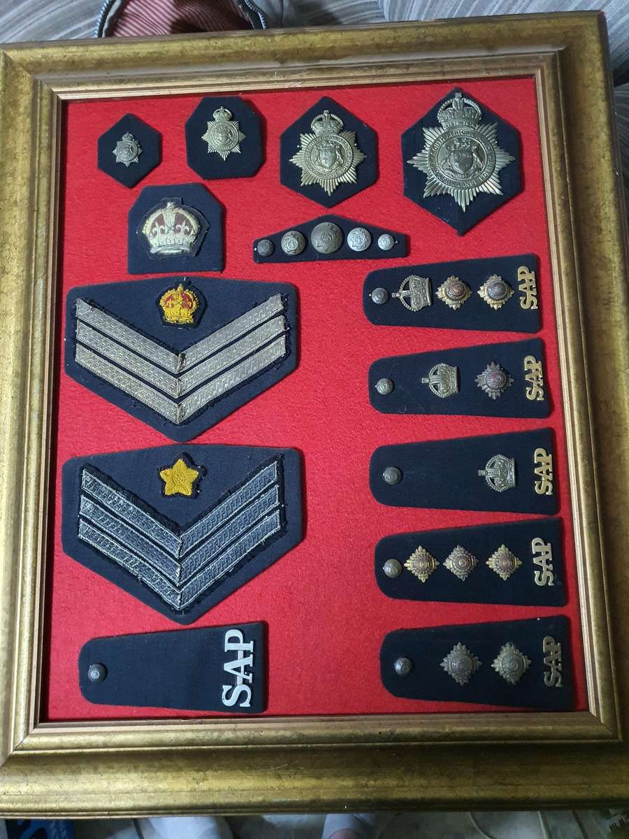 Frame containing 1926 SA Police ranks and helmet badges