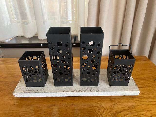 Set of 4 tea light candle lanterns on wooden block.