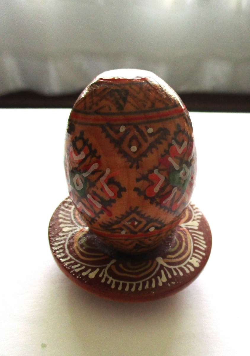 Stunning  painted wooden egg on a wooden stand