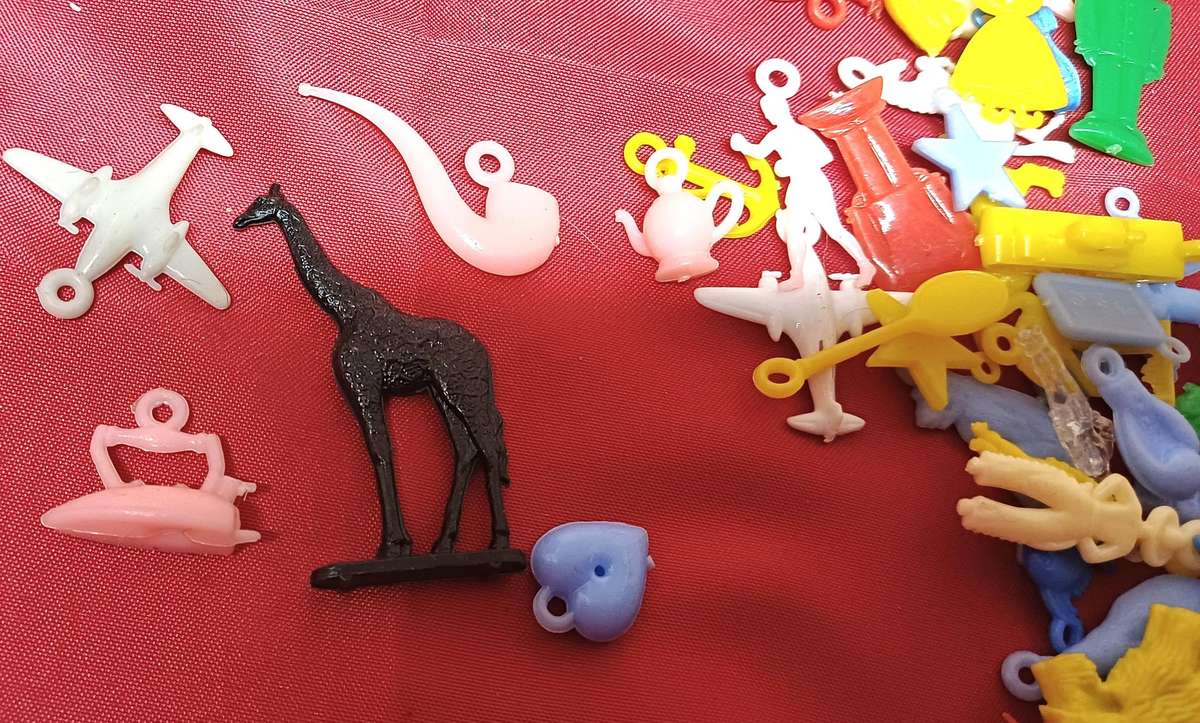 Collectable tin full of vintage plastic charms