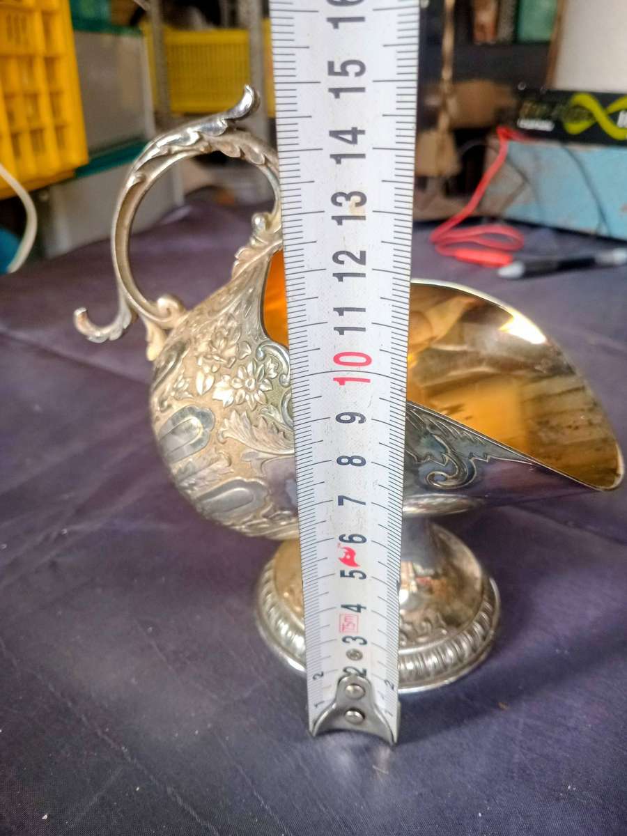 silver-plated sugar scuttle, often featured in Victorian-style tea services, is designed to hold and