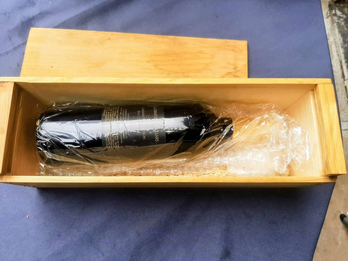 Cabernet Sauvignon, presented in a wooden gift box. The bottle is wrapped in plastic and packing