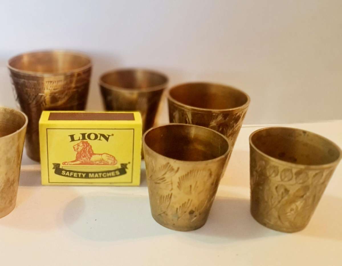 7 brass shot glasses. Various sizes