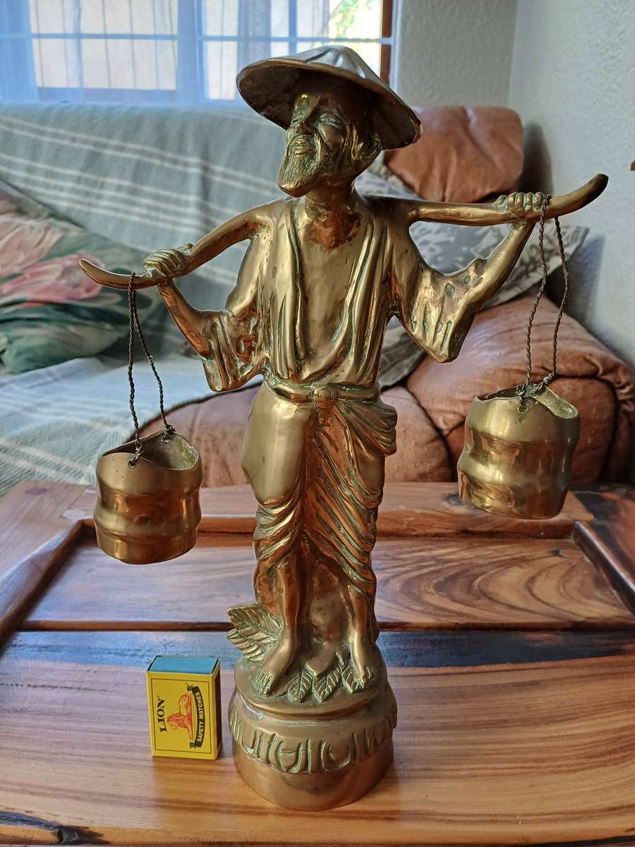 Brass sculpture of man carrying water buckets