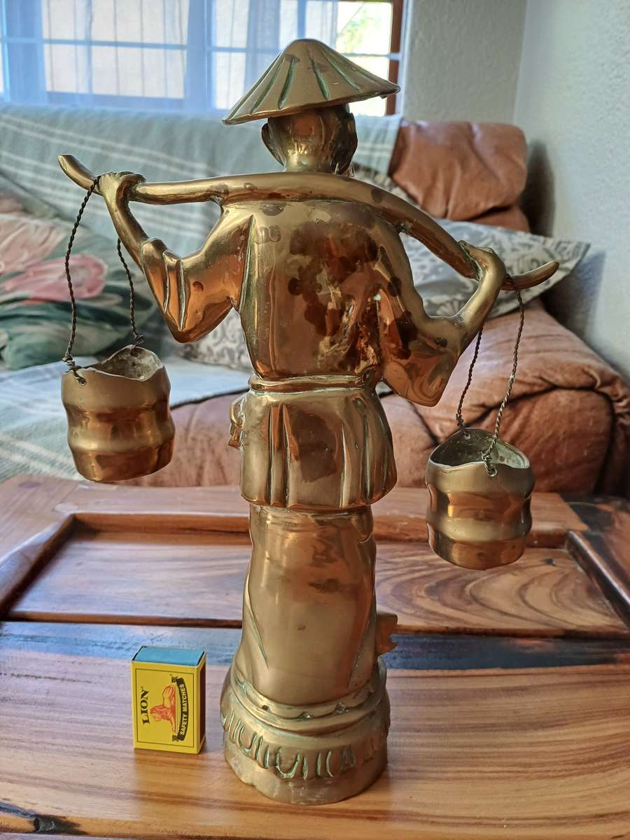 Brass sculpture of man carrying water buckets