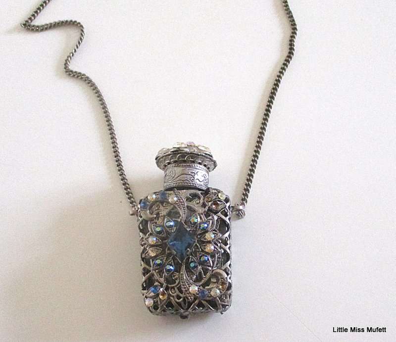 A silver tone Czech Perfume bottle on a long chain