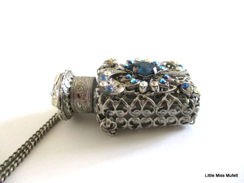 A silver tone Czech Perfume bottle on a long chain