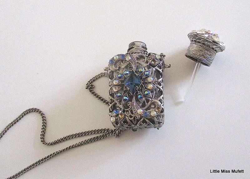 A silver tone Czech Perfume bottle on a long chain