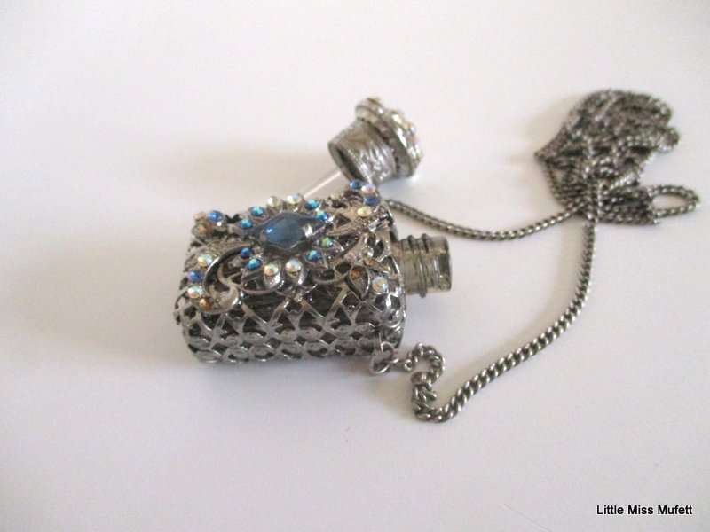 A silver tone Czech Perfume bottle on a long chain