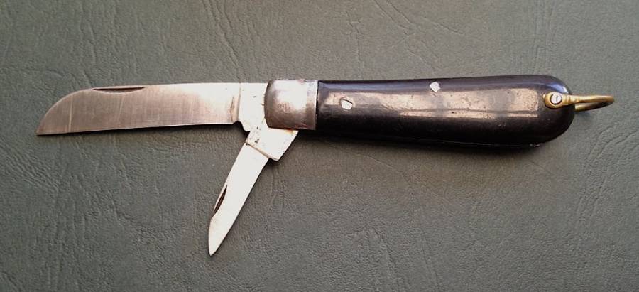 Vintage carbon steel pocket knife, unused in original brown paper wrapping.